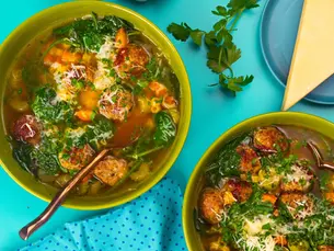 An overhead shot of two bowls of soup with meatballs and herbs.