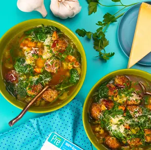 An overhead shot of two bowls of soup with meatballs and herbs.