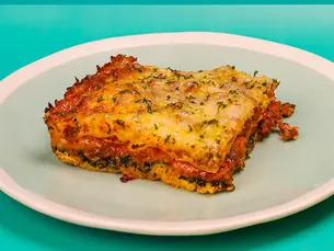 A big square piece of lasagna with ground beef and cheese on a plate.