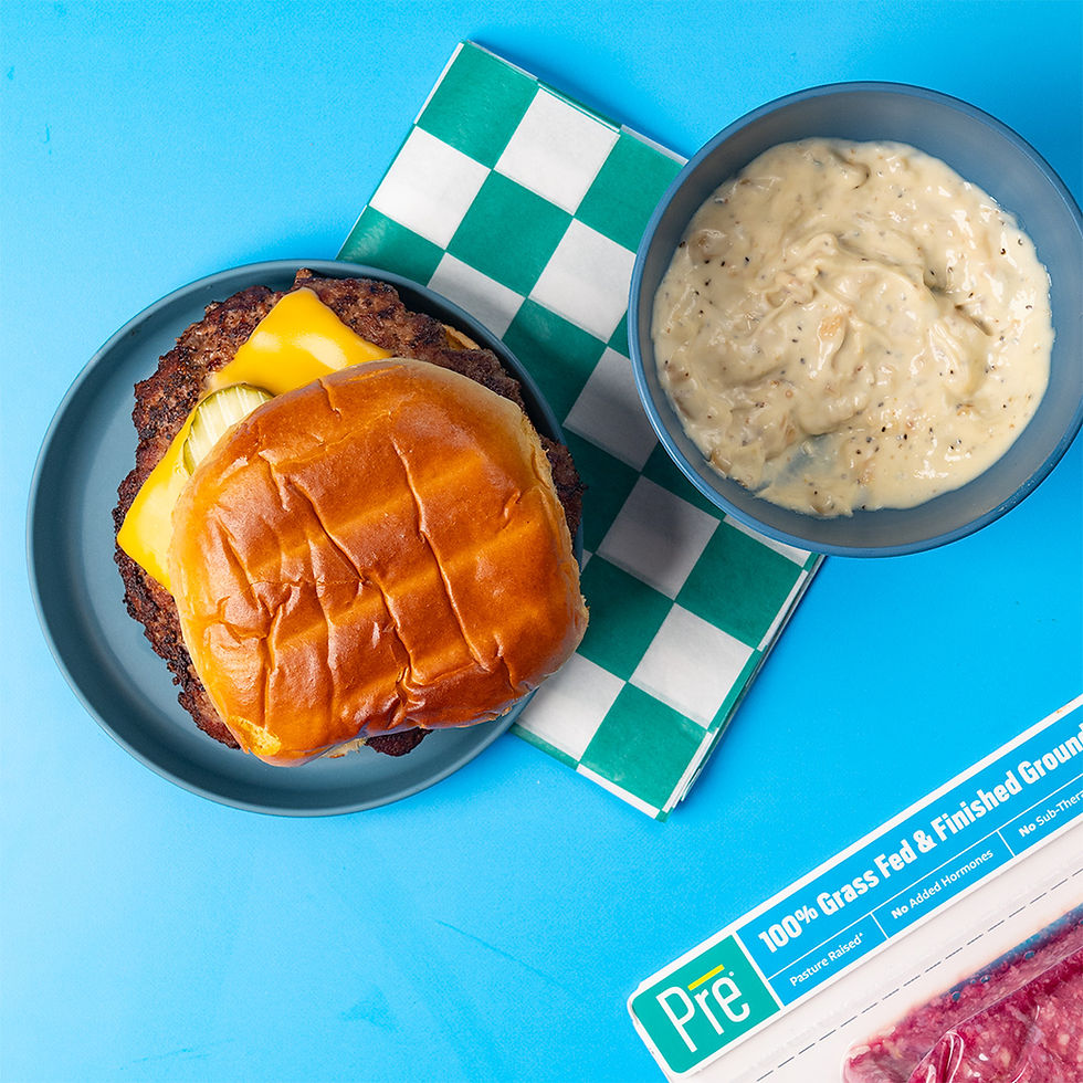 An overhead shot of a cheeseburger next to a bowl of sauce and a package of Pre 85% Lean Ground Beef.
