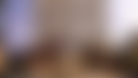 Rendering of a modern, multi-story residential building with balconies is set against a twilight sky. Warm lights from windows and streetlamps create an inviting atmosphere.