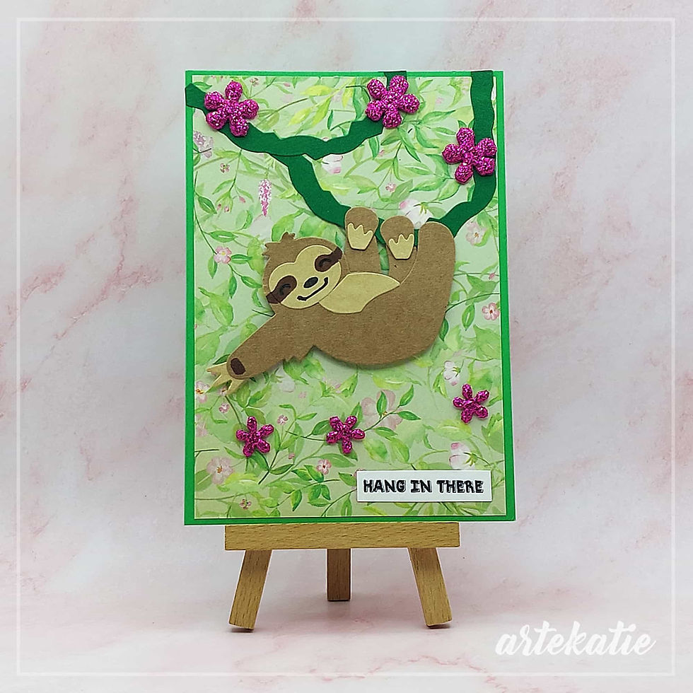 Handmade card featuring sloth hanging on a tree on green background