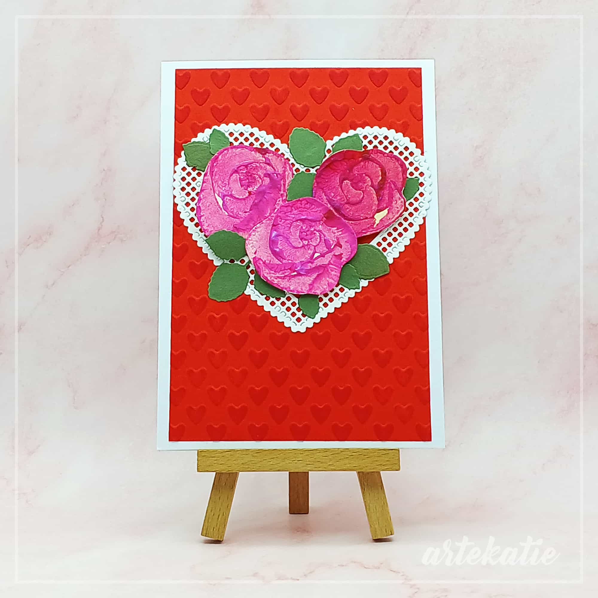 handmade card with red background featuring 3 roses in a heart
