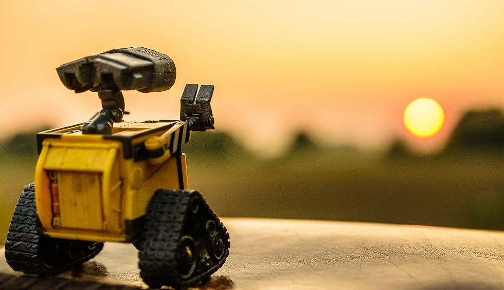 A yellow robot looks out at the sunset contemplating its role in the universe.