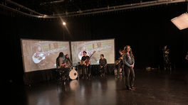 Female singer performing on stage with band and projected visuals in the background