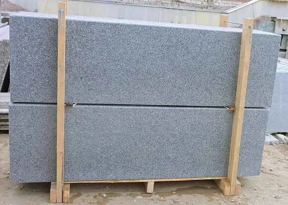"Granite slabs tightly compressed in sturdy wooden bundles with plastic sheets separating them."
