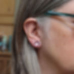 Light sky blue and red interchangeable silver stud earrings on a white woman