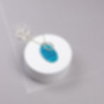 Turquoise blue silver cluster duo necklace on a white round plinth on a grey background