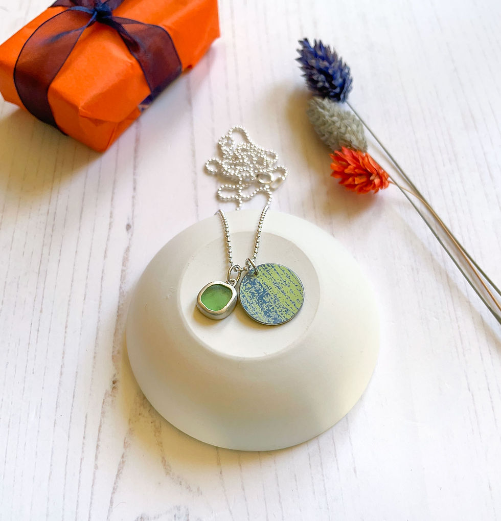 Thumbnail: Green and blue sea glass and aluminium silver cluster necklace on up turned white trinket dish with gift and flowers behind