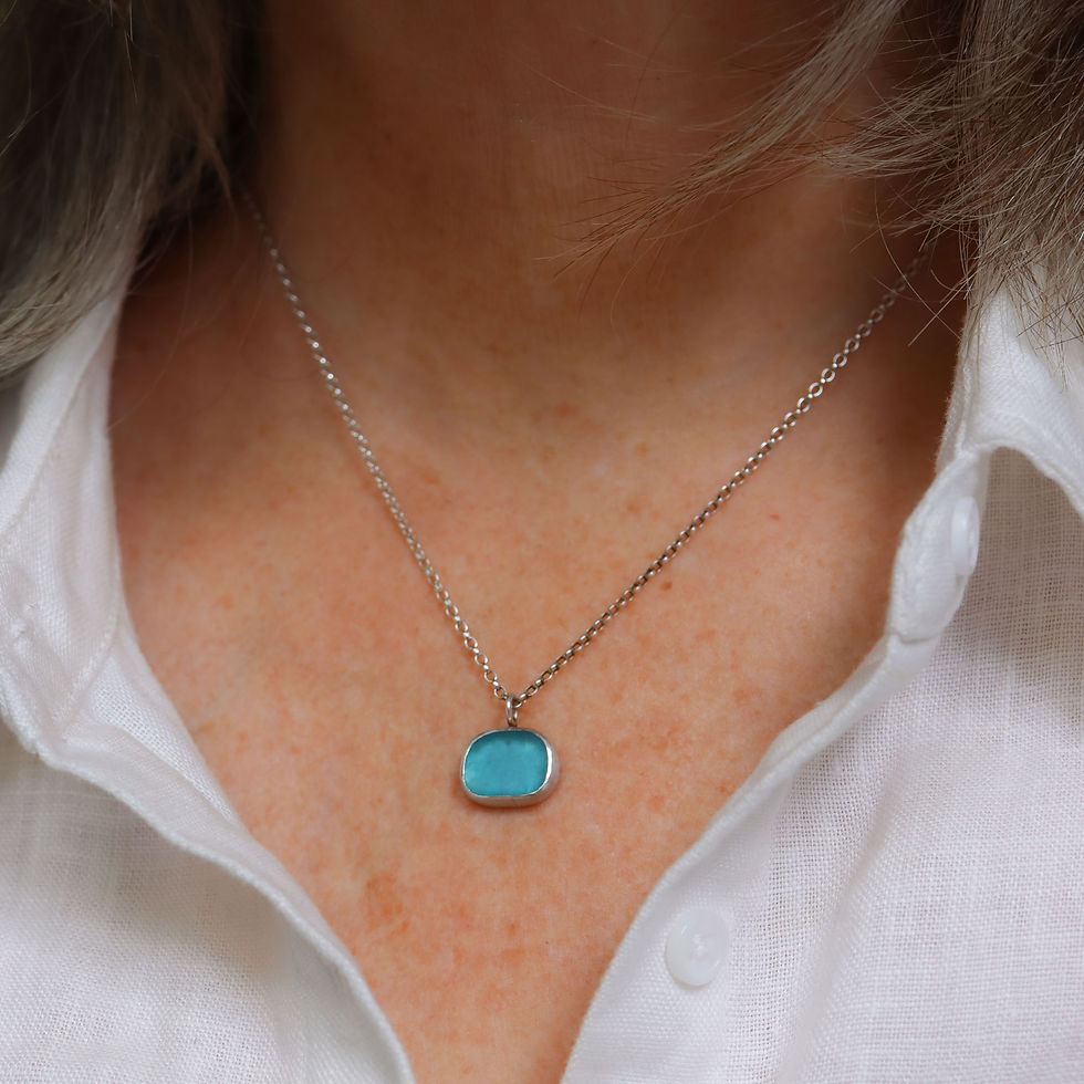 Thumbnail: Turquoise blue sea glass and silver necklace on a white woman wearing a cream linen shirt