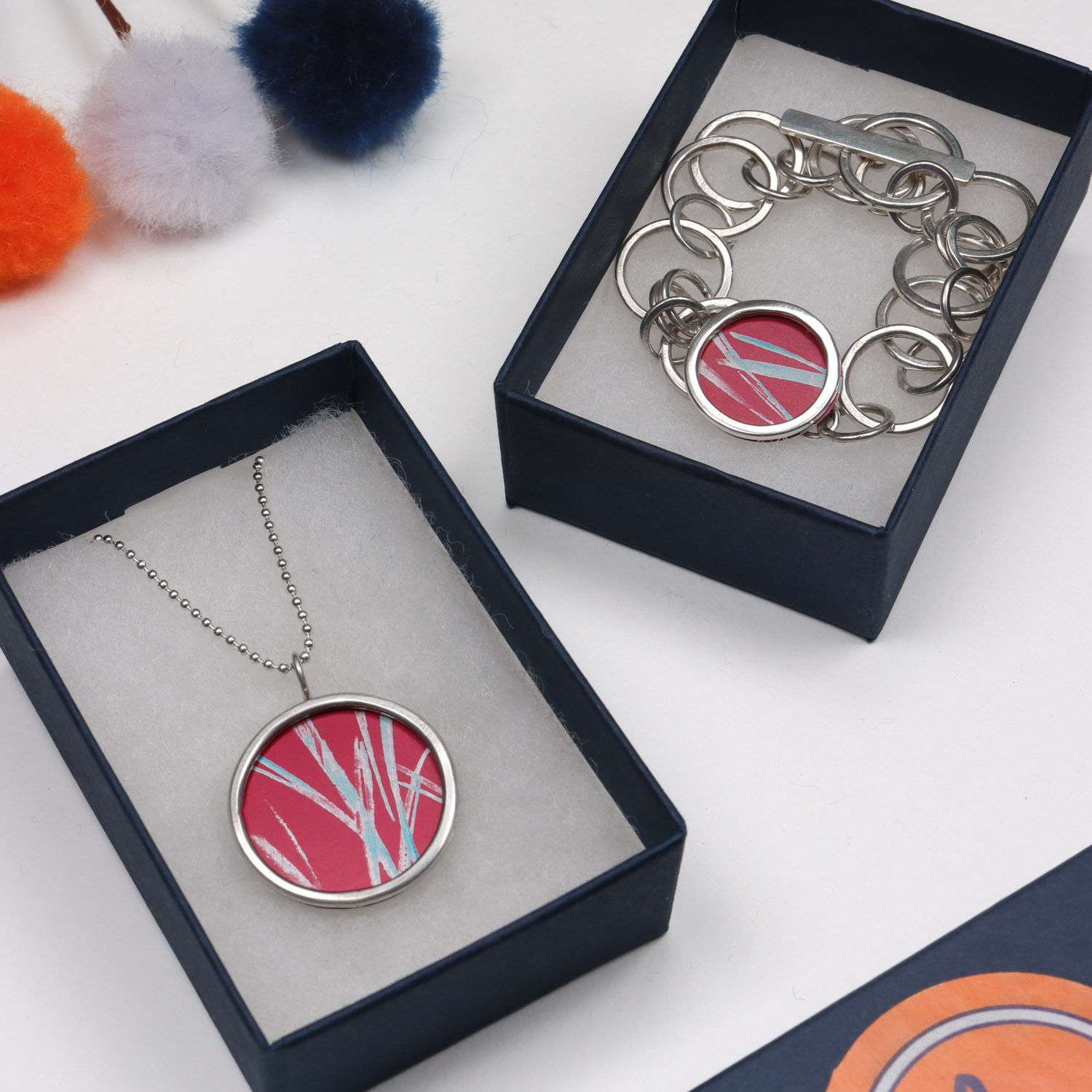 Red and turquoise aluminium and silver rivet necklace and matching bracelet on a white background