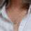 Thumbnail: Violet blue sea glass and silver minimalist pendant necklace on a white woman in a cream linen shirt