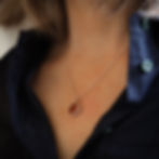 Thumbnail: Dark orange sea glass and silver pendant necklace on a white woman wearing a dark blue shirt