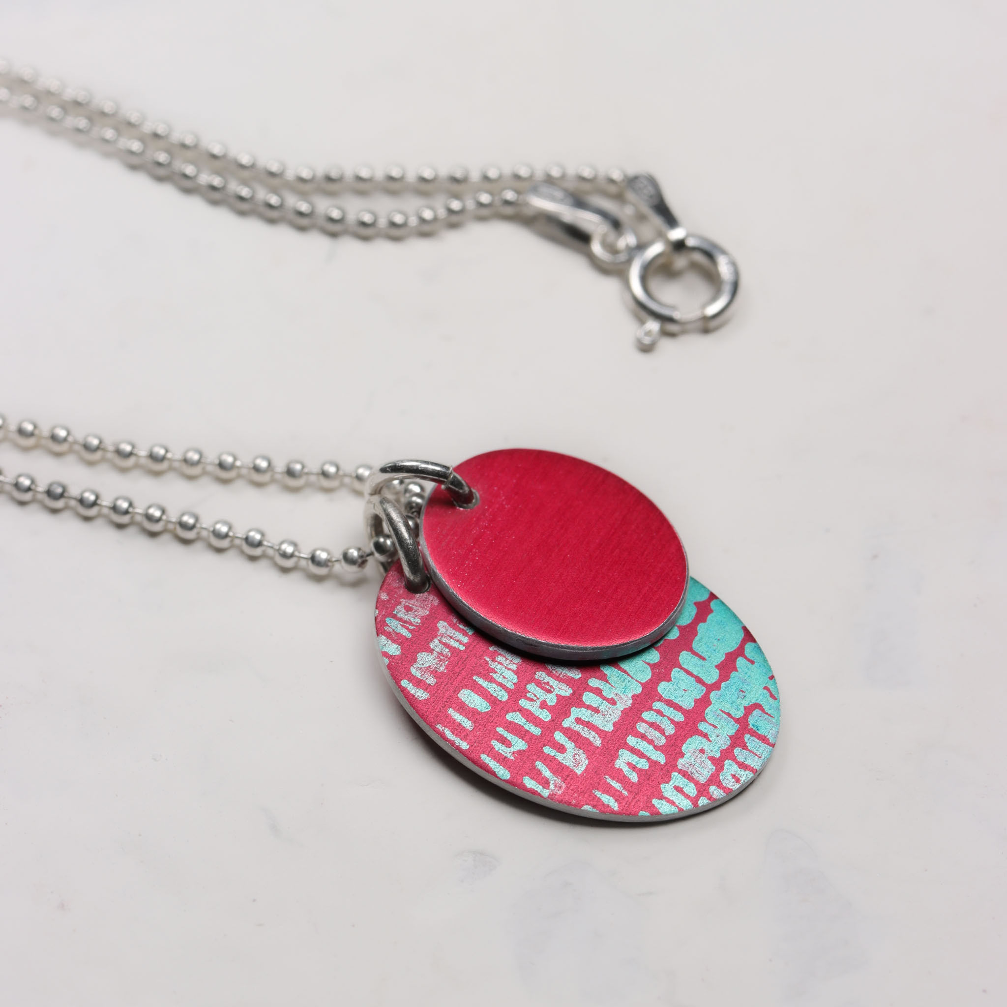 Pink red and turquoise oval cluster necklace on a white background