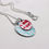 Thumbnail: Two ovals one light blue, one red on a silver chain on a white background