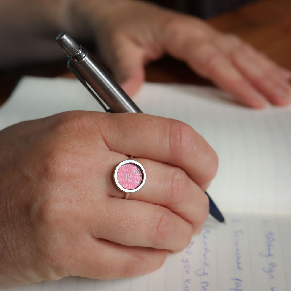 Rose pink aluminium silver rivet ring on a white woman with pen and notebook