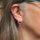 Thumbnail: Pink oval earrings with a turquoise fern pattern on and silver circle stud earrings on white woman