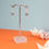Thumbnail: Teal blue and orange mini horizontal oval drop earrings on an earring stand on an orange background