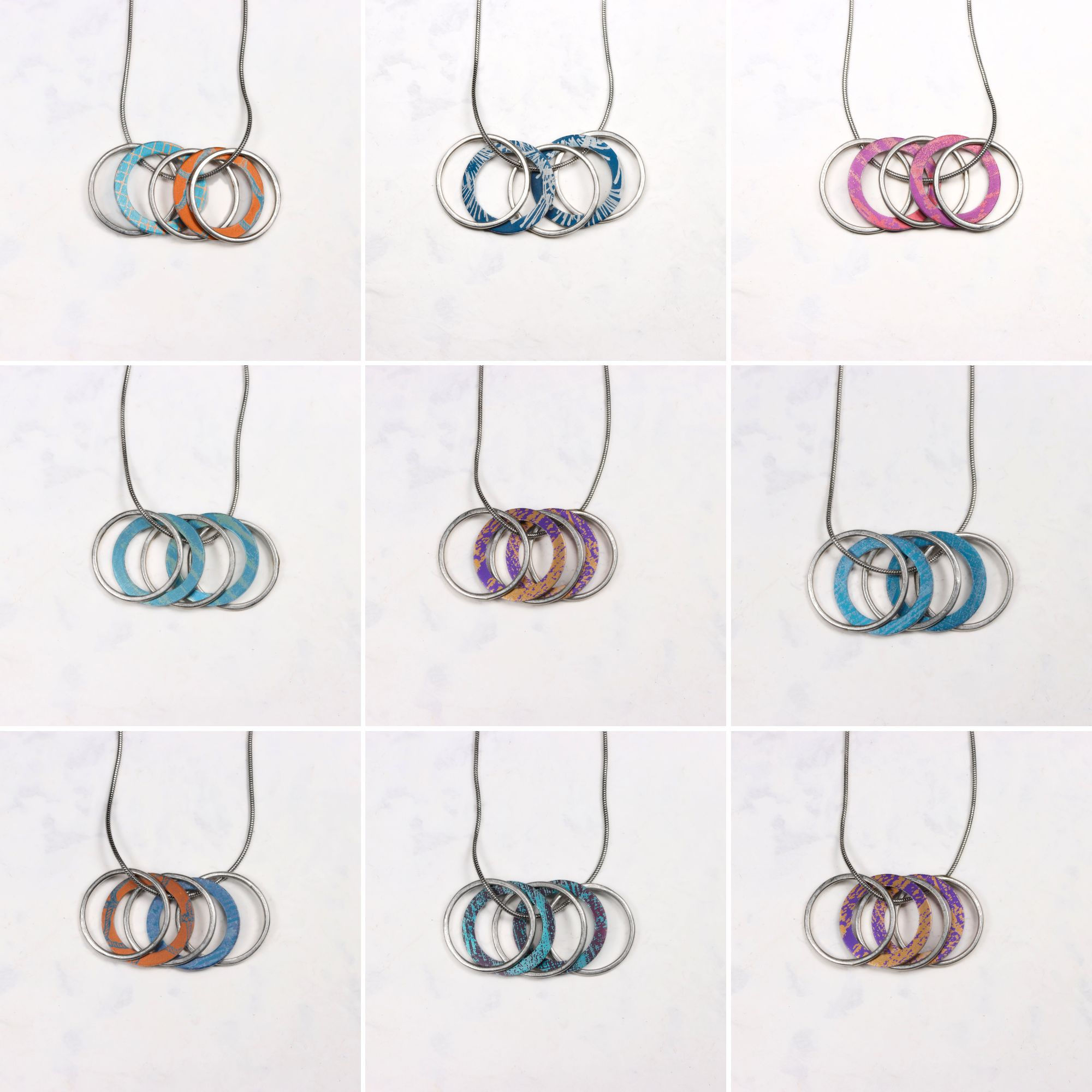 Five hoop aluminium and silver necklaces on a white background