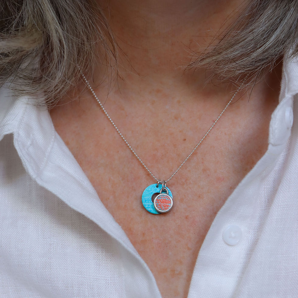 Thumbnail: Turquoise washer disc and orange and silver cabochon necklace with silver chain on a white woman wearing a cream linen shirt