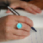 Turquoise blue aluminium silver rivet ring on a white woman with pen and notebook