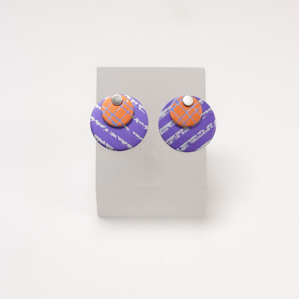 Purple and orange 3 in 1 silver stud earrings on an earring stand on a white background