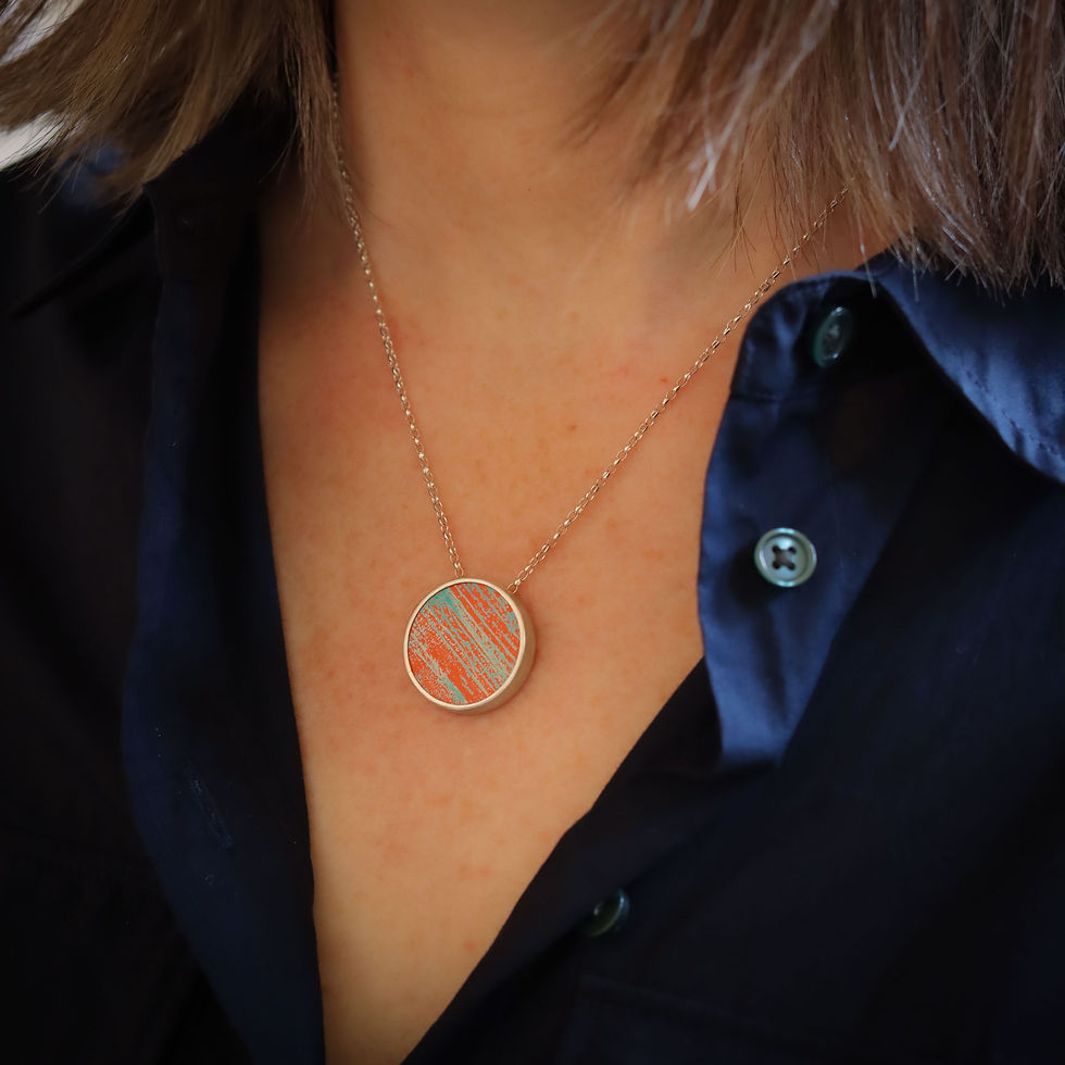 Thumbnail: Orange and turquoise aluminium and silver round pendant necklace on a white woman wearing a dark blue shirt