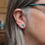 Thumbnail: Little turquoise blue anodised aluminium and silver stud earrings on a white woman