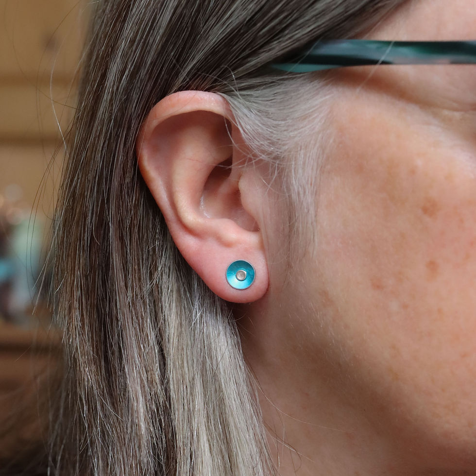 Little turquoise blue anodised aluminium and silver stud earrings on a white woman