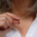 Thumbnail: Dark orange sea glass and silver pendant necklace on a white woman wearing a cream linen shirt