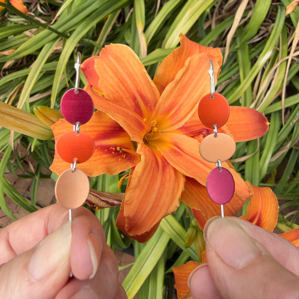 Thumbnail: Day lily triple aluminium earrings in front of a day lily
