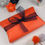 Thumbnail: Jewellery box gift wrapped in orange tissue paper with blue organza ribbon