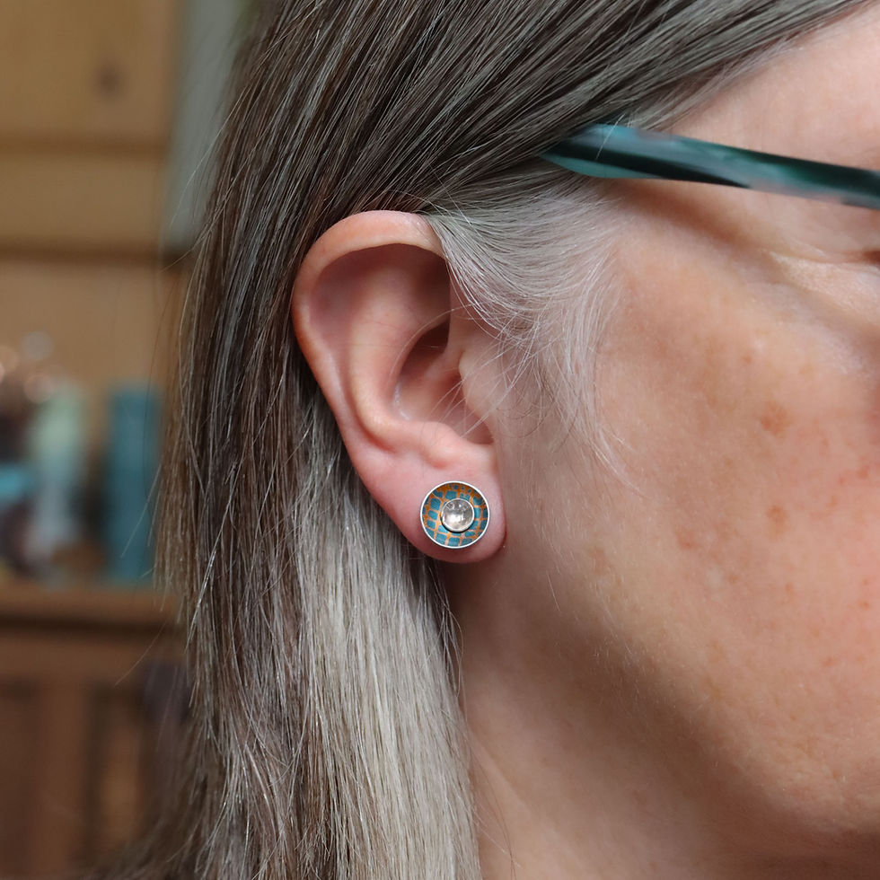 Teal and orange aluminium and silver interchangeable stud earrings on a white woman