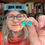Thumbnail: Aqua green sea glass cabochon silver stud earrings being held by the jeweller in her studio