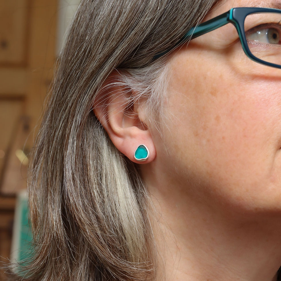 Triangular teal green sea glass and silver stud earrings on a white woman