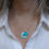 Thumbnail: Turquoise washer and disc cluster pendant necklace on a white woman wearing a cream linen shirt