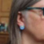 Blue and green 3 in 1 stud earrings on a white woman