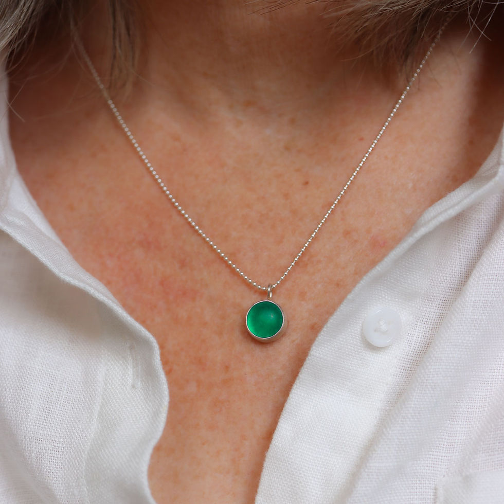 Emerald green sea glass cabochon silver cute necklace on a white woman wearing a cream linen shirt