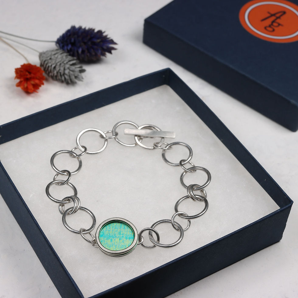 Thumbnail: Green and turquoise blue anodised aluminium and silver chain bracelet in dark blue open jewellery box with lid behind