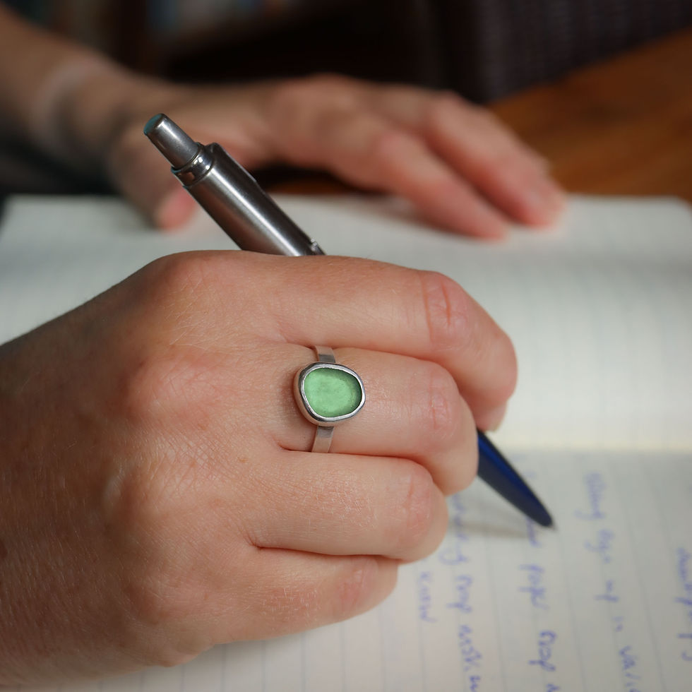 Spring green sea glass and silver cabochon ring on a white woman with a pen and notebook