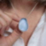 Thumbnail: Large blue sea glass and silver pendant necklace on a white woman in a cream linen shirt