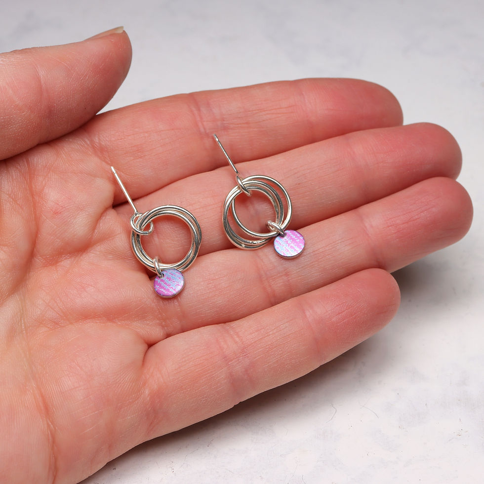 Thumbnail: Magenta pink and mauve blue aluminium and 3 silver ring earrings in a white woman's hand