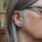 Turquoise blue aluminium and silver stud earrings on a white woman