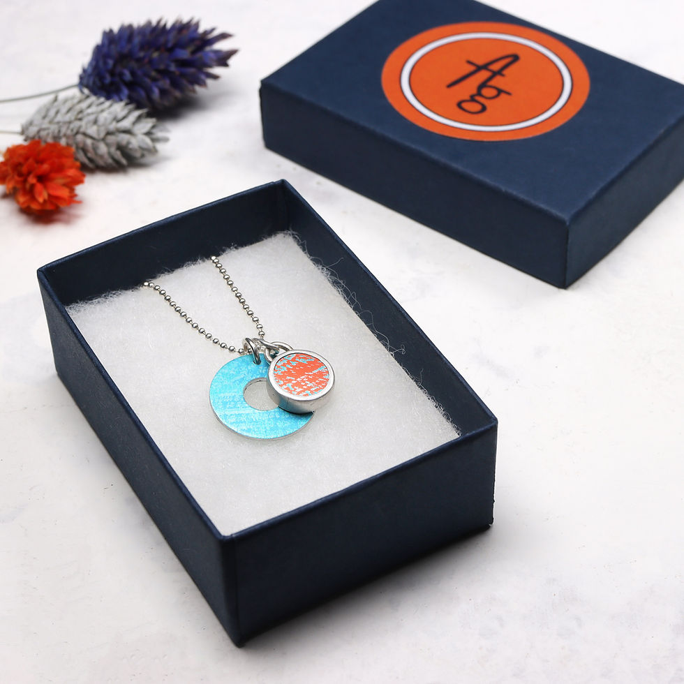 Thumbnail: Turquoise and orange silver necklace in dark blue jewellery box on white background with dried flowers