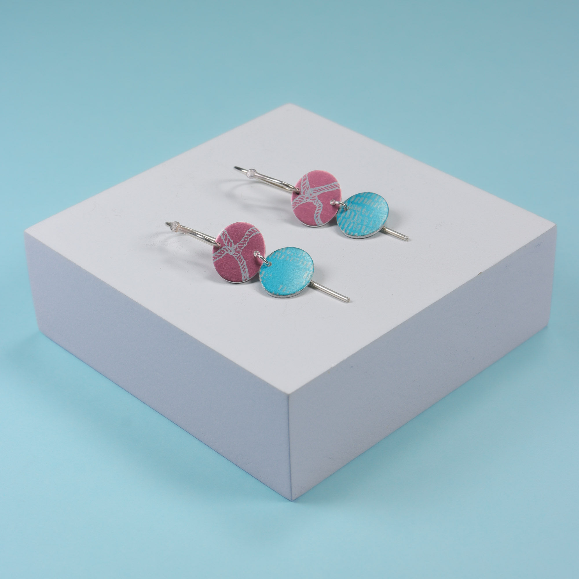 Pink and turquoise double oval earrings on a blue background