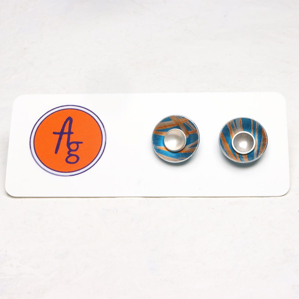 Thumbnail: Teal green and orange aluminium and silver interchangeable silver stud earrings on a display card on a white background