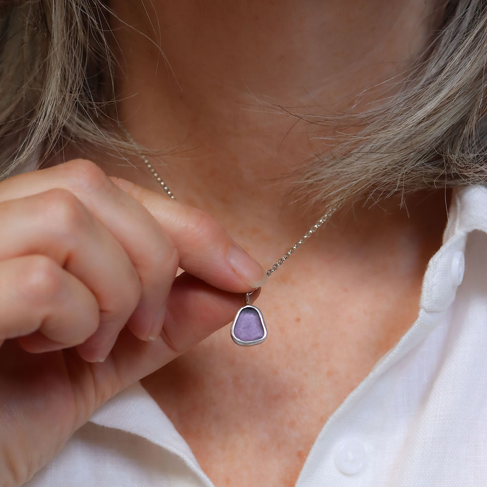 Thumbnail: Small purple sea glass and silver necklace on a white woman wearing a cream linen shirt