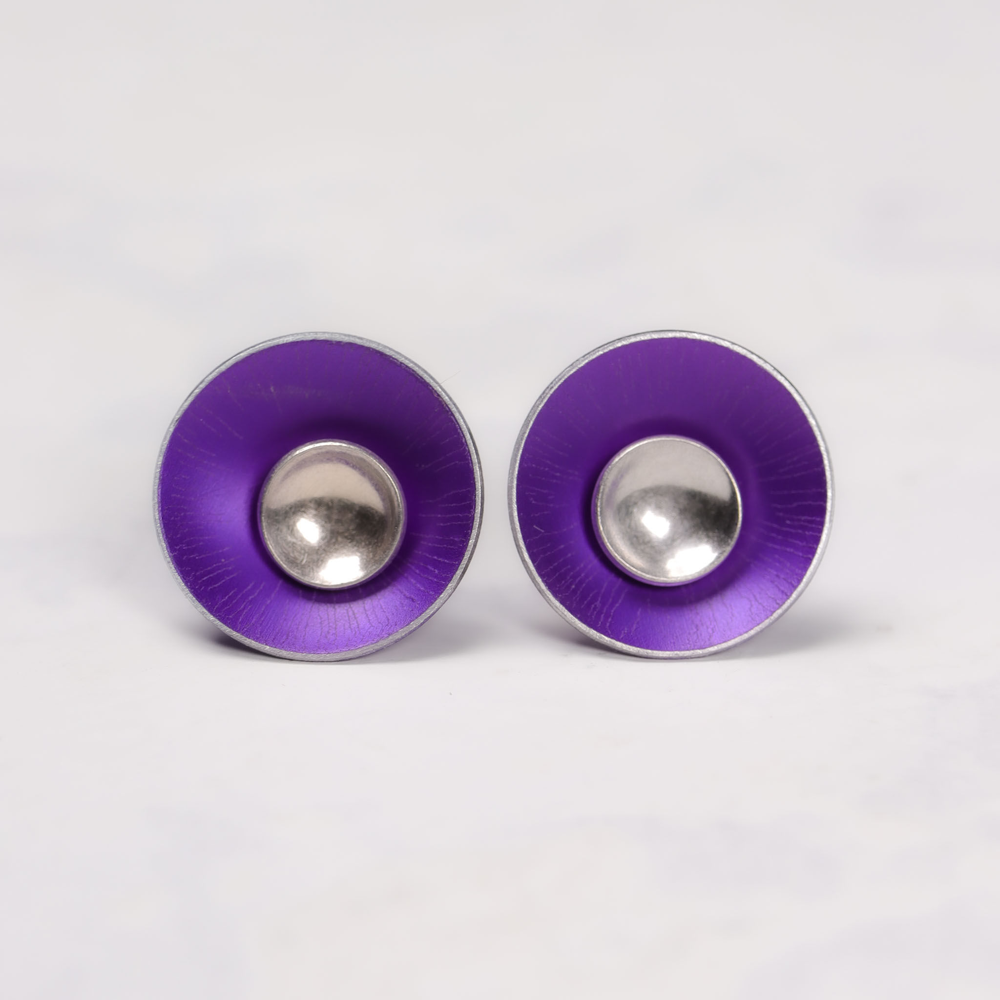 Purple aluminium and silver stud earrings on a white background