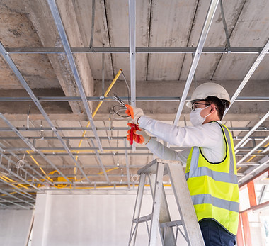 Asian handsome electrician wearing a mask installing laying electrical cables on the ceili
