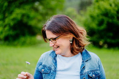 Frau bei einer Fotosession am Maltschacher See in Kärnten, umgeben von Natur mit Getreidefeldern und frisch gemähtem Gras, entspannt im Moment und die Umgebung genießend.